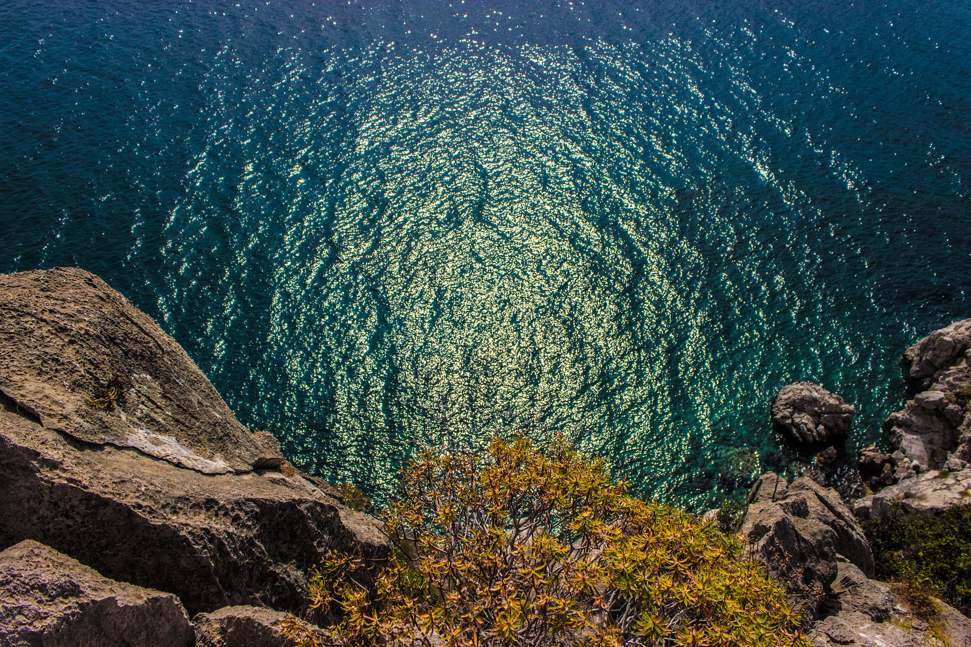 scary view over a tree-lined cliff into blue water